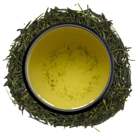 A cup of thick yellow-green gyokuro seen from above, ringed by dark shade-grown gyokuro leaves on a white background